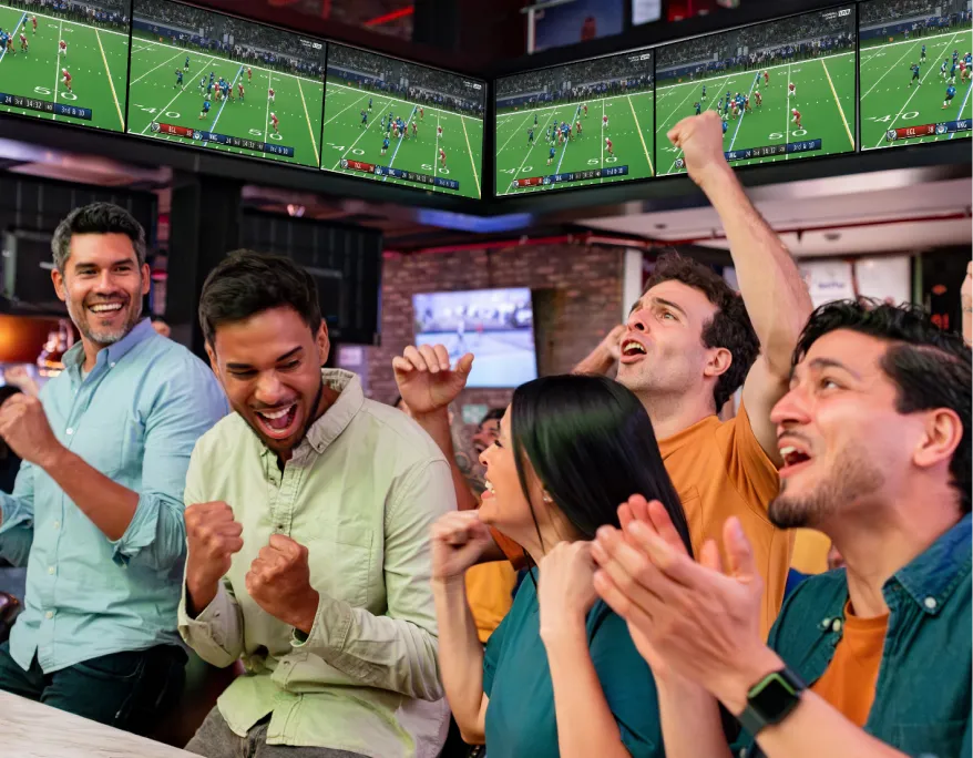 Customers celebrating and cheering with TV screens lining the walls of a restaurant or bar